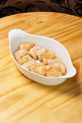 Delicious portion of fried pastries served in a white ceramic bowl on a wooden table.