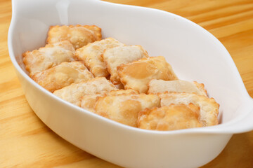 Delicious portion of fried pastries served in a white ceramic bowl on a wooden table.