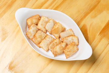 Delicious portion of fried pastries served in a white ceramic bowl on a wooden table.
