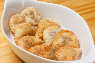 Delicious portion of fried pastries served in a white ceramic bowl on a wooden table.