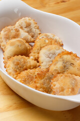 Delicious portion of fried pastries served in a white ceramic bowl on a wooden table.
