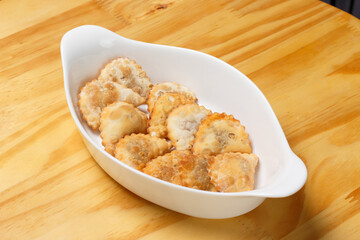 Delicious portion of fried pastries served in a white ceramic bowl on a wooden table.