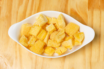 Delicious portion of fried manioc, or cassava, served in a white ceramic bowl on a wooden table.