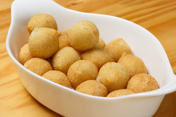 Delicious portion of fried cheese ball served in a white ceramic bowl on a wooden table.