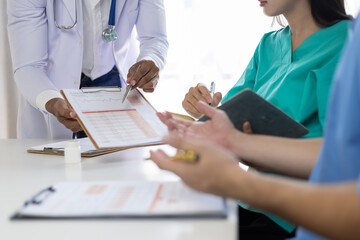 Doctor meeting discussing patient treatment plan. Healthcare professionals having a meeting in a hospital room, analyzing medical records and discussing a patient's diagnosis and treatment plan.