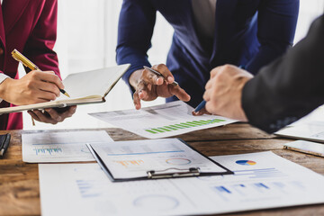 Business people analyzing financial documents, discussing charts and graphs showing company growth...
