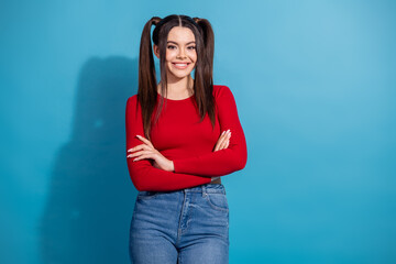 Young woman in red top with ponytails posing confidently against blue background showcasing...