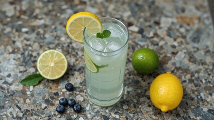 Fototapeta premium Summer's perfect cold drink: lemonade with citrus fruits and blueberries displayed on stone.