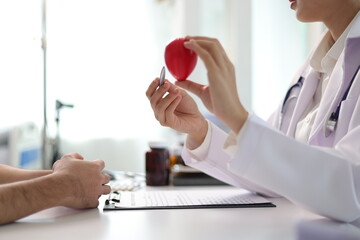 Doctor explaining cardiovascular system to patient using anatomical model. Consultation in medical...