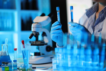 Medical scientist analyzing test tube with blue liquid in laboratory.