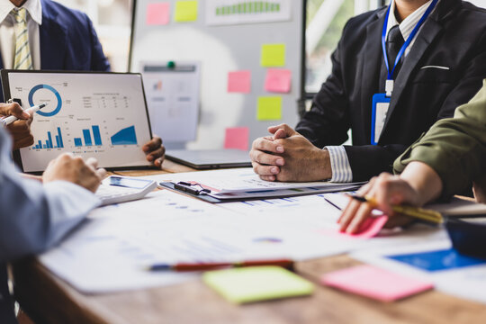 Business people are discussing company performance and analyzing charts and graphs showing positive growth during a corporate meeting.