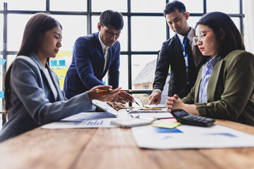 Business team analyzing data and discussing financial strategy in office meeting, collaborating on charts and reports to achieve shared goals.