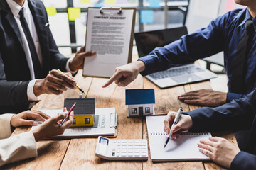 Real estate agents are presenting contract agreements and discussing housing projects with clients.