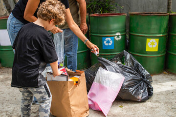 Family recycling paper and plastic in separate bins