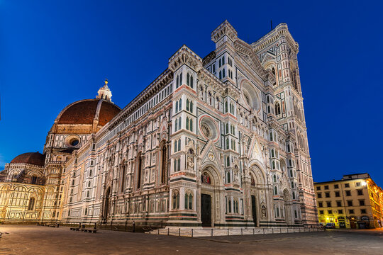 View of the majestic Duomo, adorned with intricate white and green marble facades, rises against the deepening twilight sky, Florence, Tuscany, Italy.