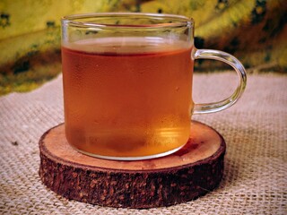 Steaming Herbal Tea in Glass Mug on Rustic Wood Coaster.