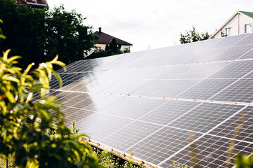 Close-up of solar panels near house on grass in sunny outdoor setting.