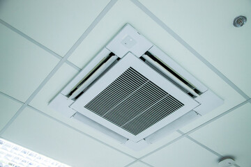 Ceiling-mounted air conditioner with integrated light and speaker, showcasing modern HVAC design..