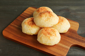 Heap of delectable homemade Brazilian cheese breads or Pao de Queijo on a wooden breadboard