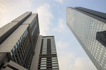 Three modern skyscrapers with glass and concrete facades rise against a partly cloudy sky, representing urban growth and architectural design.