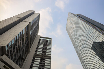 Three modern skyscrapers with glass and concrete facades rise against a partly cloudy sky, representing urban growth and architectural design.