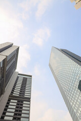 Three modern skyscrapers with glass and concrete facades rise against a partly cloudy sky, representing urban growth and architectural design.