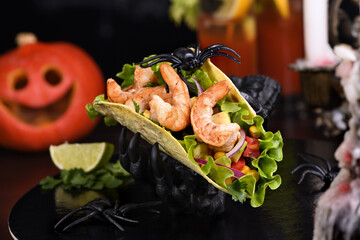 Black monster hand holding tacos crispy fried shrimp. Halloween party serving