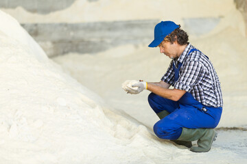 Male farmer checks the quality of powdered cow feed at a farmer's warehouse. Farmer chooses...