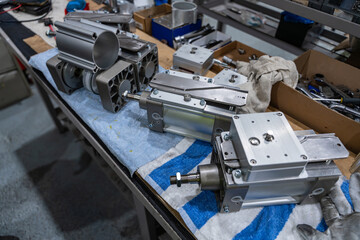 Vérins hydrauliques posés sur un établi dans un atelier, entourés d’outils et de composants...