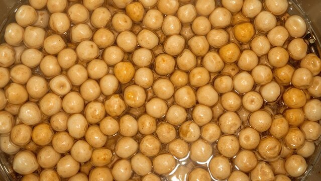 Raw soaked chick peas in water inside a cooking vessel, top view of garbanzo beans