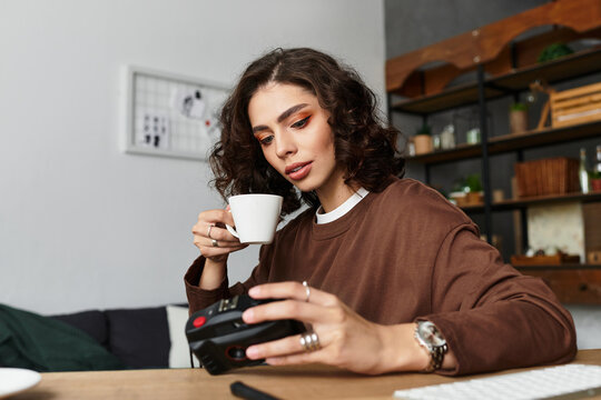 Working from home, a young woman enjoying coffee while reviewing her photography