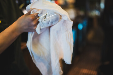 Close-up of a person polishing a glass with a white cloth in a dimly lit setting, emphasizing...