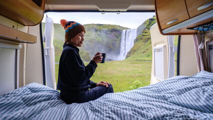 A traveler relaxes inside a cozy camper, savoring a warm drink while overlooking the majestic...