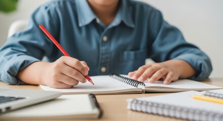 Young student focused on writing in a notebook during study session