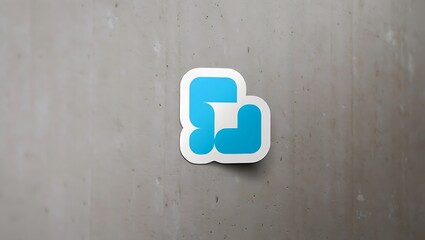 A blue and white logo sticker featuring abstract shapes on a gray textured surface in a close up shot