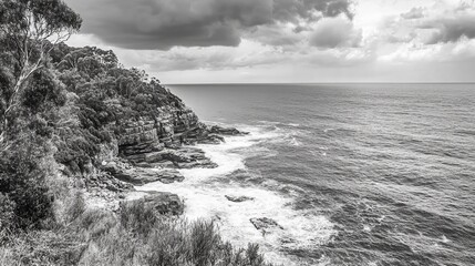 Black and white coastal view with dramatic sky and rocky shoreline