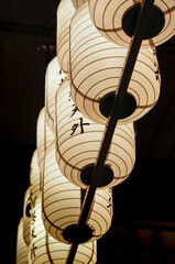 Japanese paper lanterns with symbols and  texts on them placed at the ceiling of a store for lighting and decoration