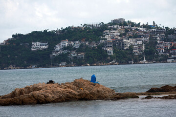 Coastal Landscape with Rocky Outcrop and Hillside Buildings Under Overcast Sky