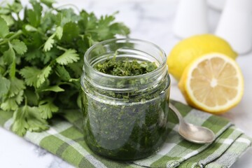 Tasty sauce with cilantro and lemons on white marble table, closeup