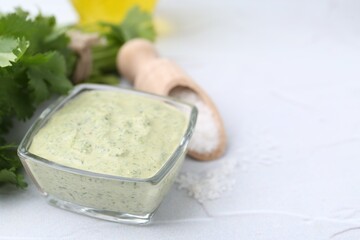 Tasty cilantro sauce in bowl and salt on light textured table, closeup. Space for text