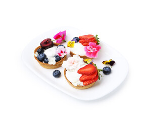 Sweet tartlets with berries and flowers isolated on white. Delicious dessert