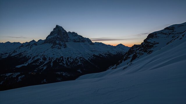 Scenic Sunset Over Snowy Mountains with a Cabin Near a Dramatic Couloir