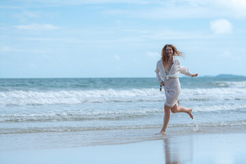 Portrait of young woman enjoying a playful walk on the beach as splash through the waves