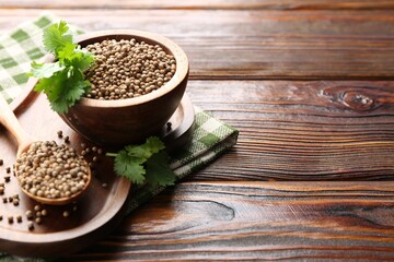 Coriander seeds and fresh cilantro sprigs on wooden table, closeup. Space for text