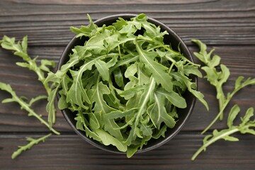 Fresh ripe green arugula leaves on dark wooden table, flat lay