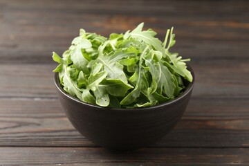 Fresh ripe green arugula leaves on dark wooden table, closeup