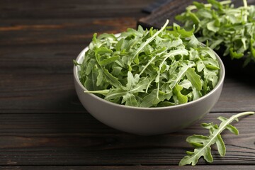Fresh ripe green arugula leaves on dark wooden table, closeup