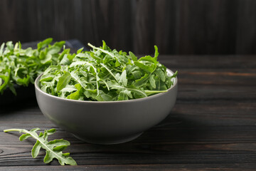 Fresh ripe green arugula leaves on dark wooden table, closeup. Space for text