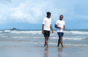 Both of friends enjoying a playful walk on the beach as splash through the waves