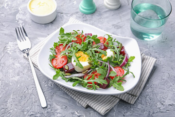 Tasty salad with arugula, vegetables and egg served on grey table, closeup
